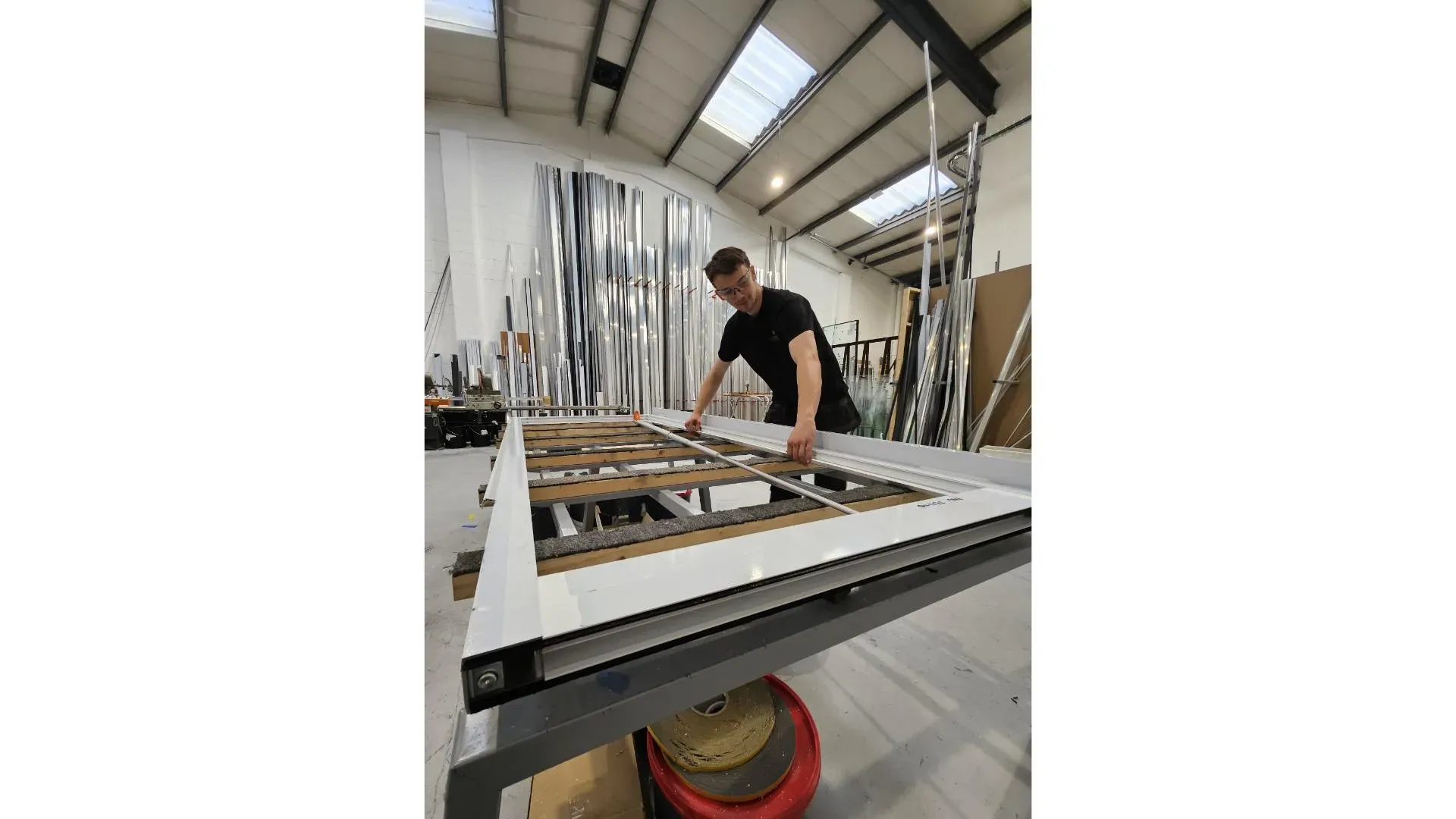 Technician beading a glazed aluminium door on a jig table