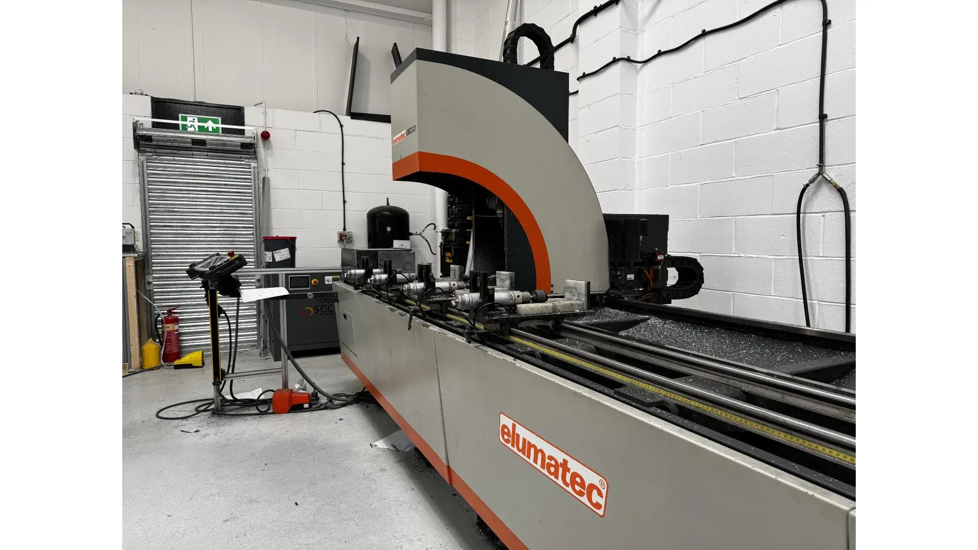 Elumatec CNC machining centre cutting hardware preps into an aluminium door profile before the corners are joined